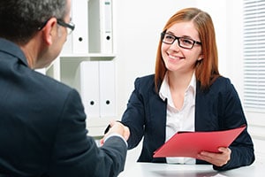 A doctor shakes her colleague's hand as she handles paperwork.